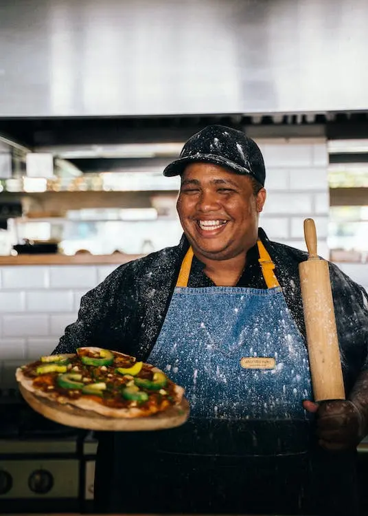 Chef Smiling and Holding a Pizza